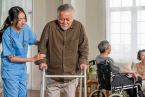 Staff assist an older resident during an emergency drill in an assisted living hallway.