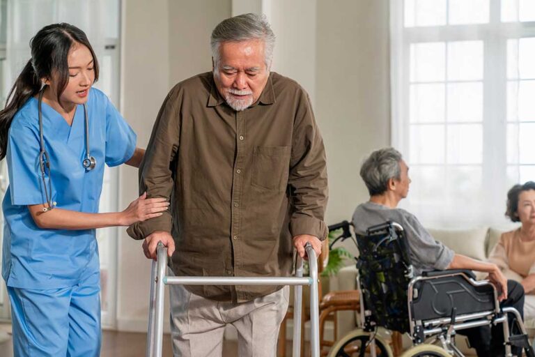 Staff assist an older resident during an emergency drill in an assisted living hallway.
