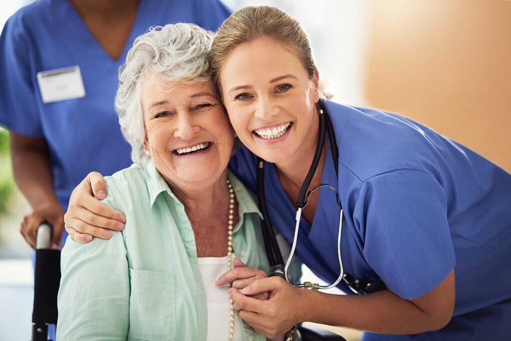 Older adult and family member organize labeled clothing, toiletries, and personal keepsakes in an assisted living room.